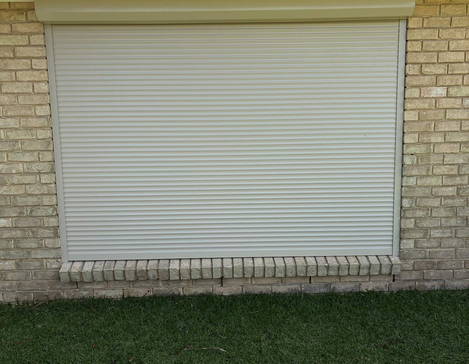 Cream roller shutter on a brick home window